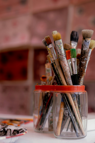 A group of paint brushes in a glass container

AI-generated content may be incorrect.