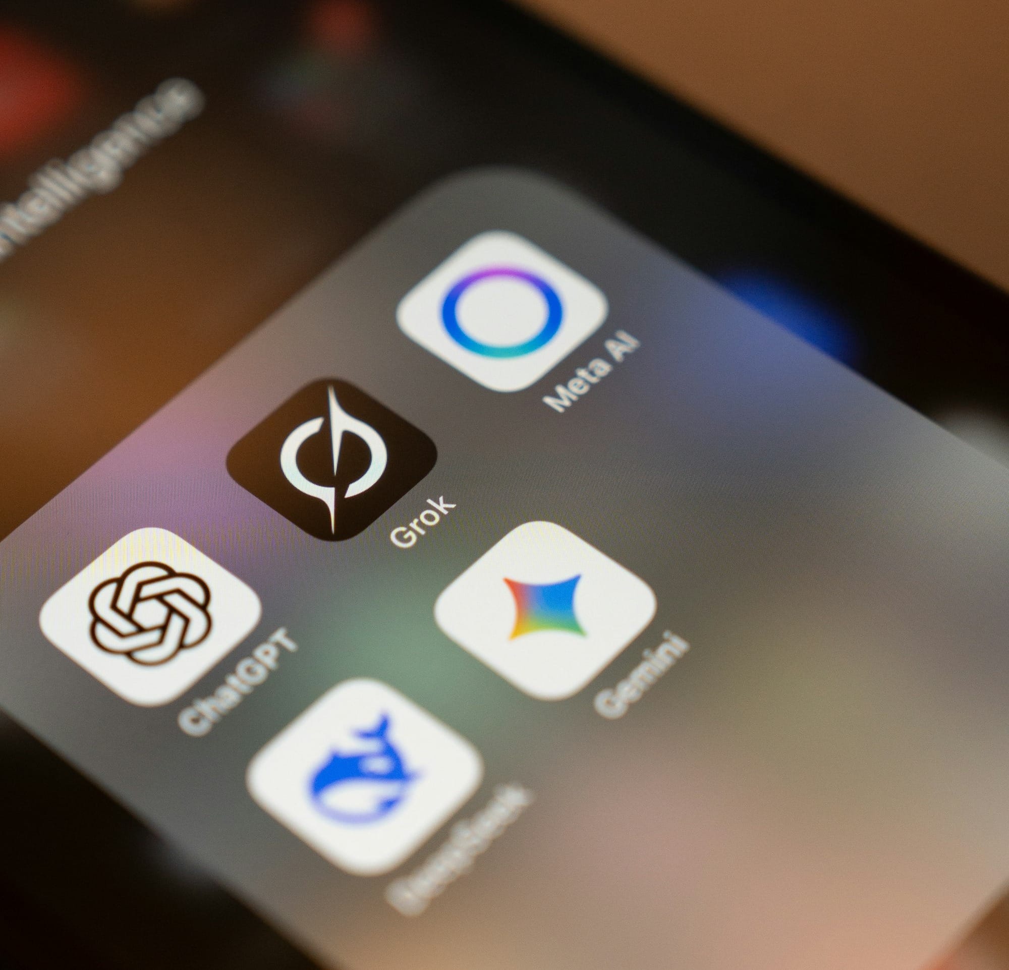 Smartphone screen displays ai app icons: chatgpt, grok, meta ai, gemini.